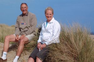 Couple sat on hedge on beach